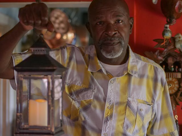 An older man holding a lantern