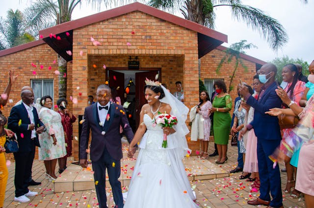 Marriage A newly-married couple leaving a church with friends and family tossing flower petals in their path