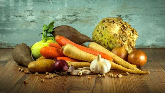 A pile of nutritious vegetables and nuts resting on a wooden table.